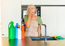 Woman at the kitchen sink holding her nose due to smelly drains