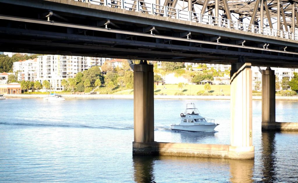 View of boat under bridge in Drummoyne. Gladesville Plumbing Services service area suburb in North Sydney.