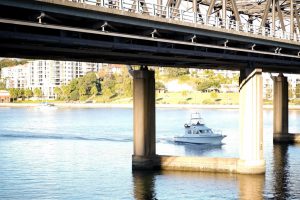 View of boat under bridge in Drummoyne. Gladesville Plumbing Services service area suburb in North Sydney.