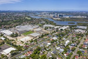 View from the sky of Ermington. View of river and CBD in background and suburbs in the foreground. Lots of trees. Gladesville Plumbing Services offers services for this area.