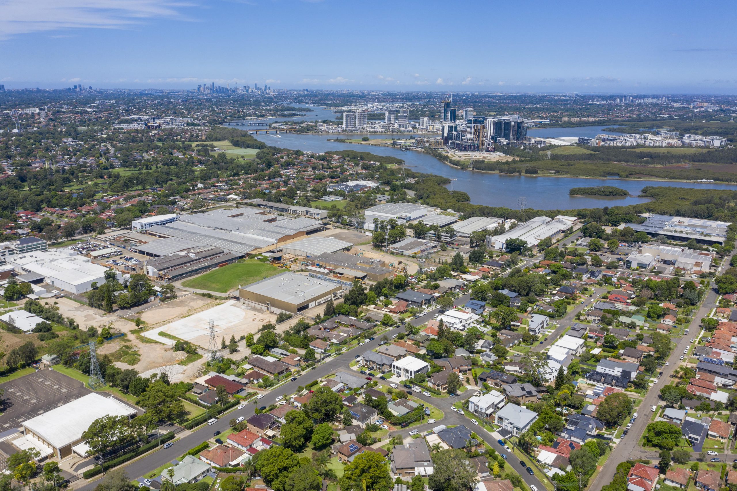 View from the sky of Ermington. View of river and CBD in background and suburbs in the foreground. Lots of trees. Gladesville Plumbing Services offers services for this area.