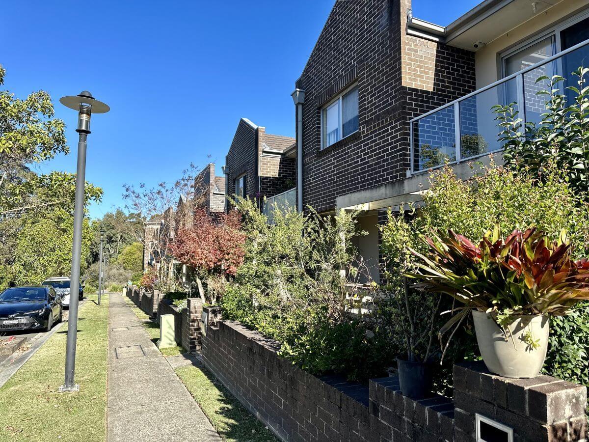 GPS Suburbs - Eastwood Street with brick townhouses and lots of greenery in Eastwood, North Sydney. Area serviced by Gladesville Plumbing Services.