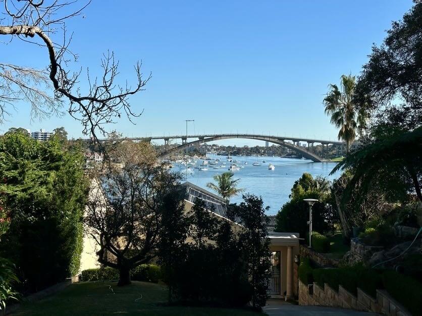 Steps down to home in Hunters Hill with bridge and river behind. Surrounded by trees. Suburb in North Sydney service area for Gladesville Plumbing Services.