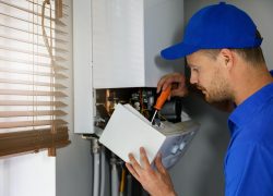 Plumber and gasfitter finishing a hot water system installation.