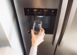 Lady filling glass from fridge with water dispenser