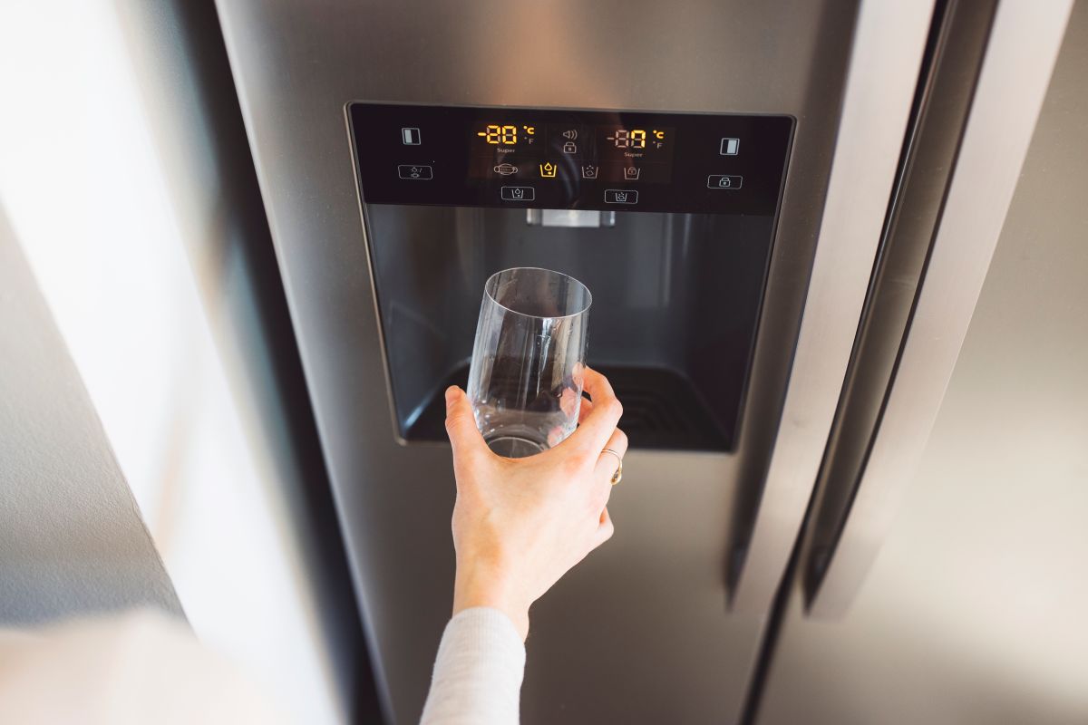 Lady filling glass from fridge with water dispenser
